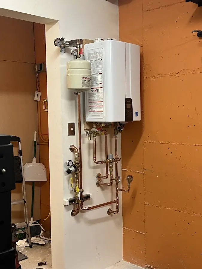Plumbing technician inspecting water heater connections in Groton